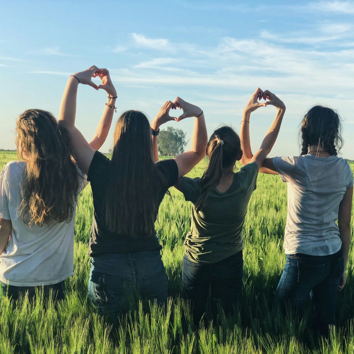 A group of girls holding heart signs learning about empathy through Life Orientation