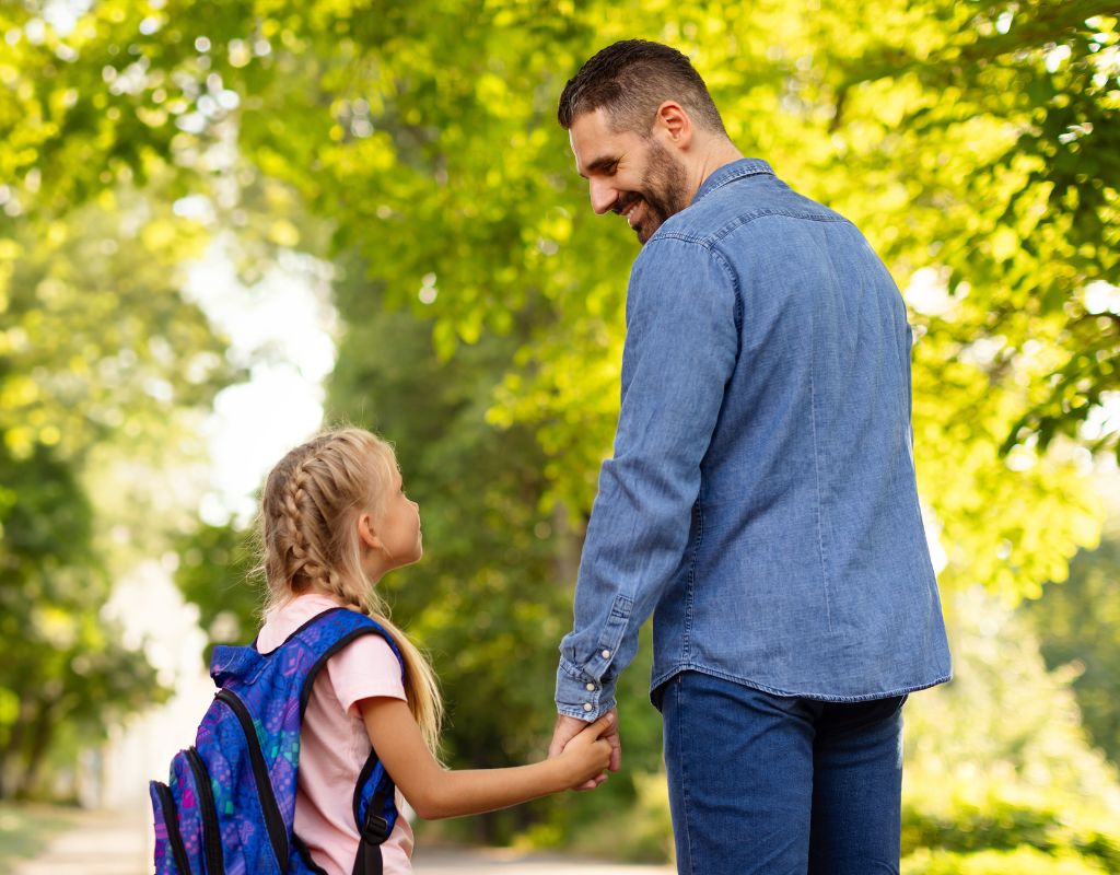 A father and daughter walking to school together holding hands