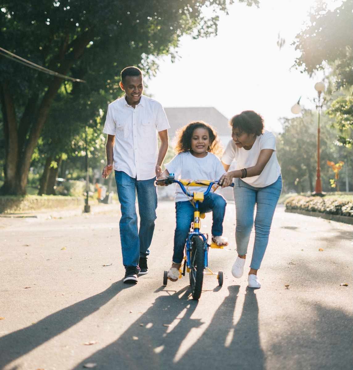Parents helping their child ride a bicycle as a stress relief activity